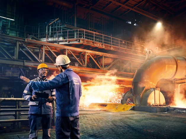 Dva inženýři diskutují v továrně na kovy.